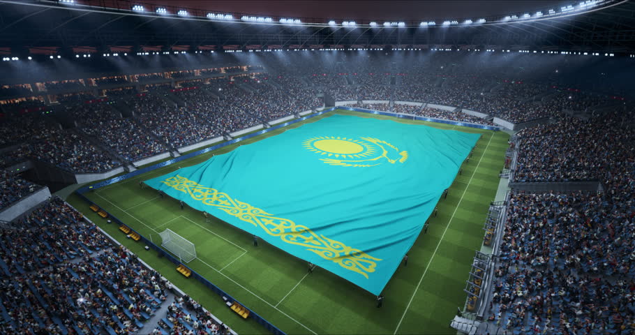 Professional Stadium Soccer Game Championship With Flag of Kazakhstan Spread Across the Pitch Before Football Match Start. Cheering Crowds of Fans Surround the Field. Aerial Elevated Static Wide Shot