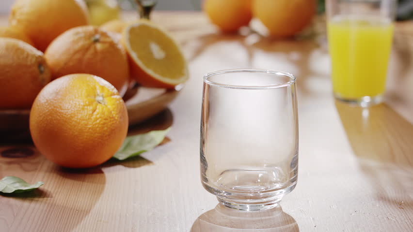 Sunlit table with fresh fruits, soft leaf shadows and orange juice being poured into glass. Summer mood, natural light, healthy lifestyle concept.
