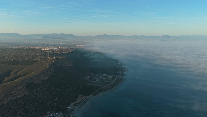 Aerial view of the santa pola lighthouse in spain overlooking the foggy mediterranean sea. Majestic view of the coastline during sunrise