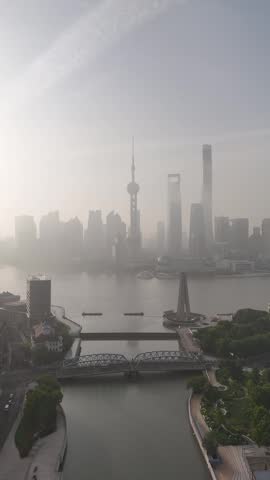 Aerial view of Shanghai skyline with fog shrouded Waibaidu Bridge over Suzhou Creek and Pudong skyscrapers, including the Oriental Pearl Tower, in thick morning haze, China.