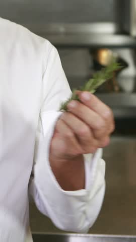 Handsome chef smelling rosemary and doing ok sign in the kitchen