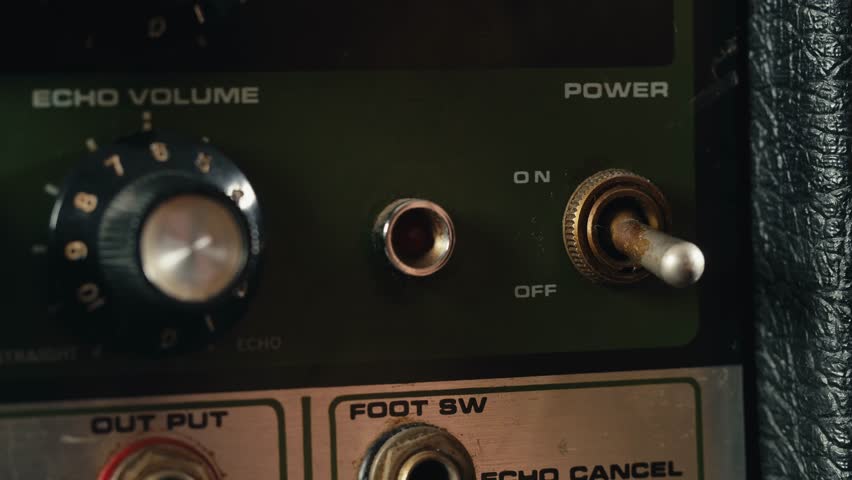Close-up of plugging a jack into a bass guitar amplifier and turning up the volume knob, live concert show, playing music on guitar tube amplifier.