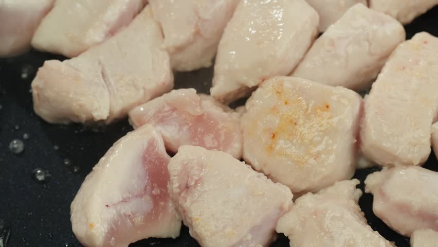 Man slicing raw turkey or chicken meat fillet on oak cutting board closeup, cooking with knife on restaurant kitchen.