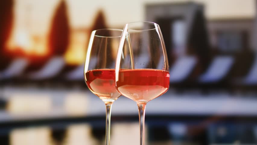 Orange or white rose wine bottle and glass against a sunset in a peaceful vineyard, pouring of ecological natural wine in hotel or sunset bar restaurant, cheers friends.