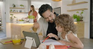Family dad guiding daughter reacting to tablet while doing homework at dining table with red pencil. Parent, child, learning, device, collaboration, kitchen, modern - Powered by Shutterstock - Get 15% off with code: PIKWIZARD15