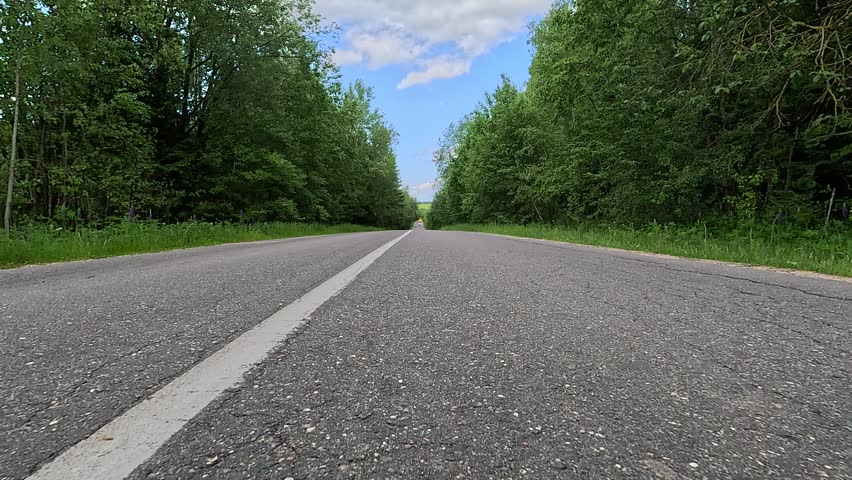 Driving a red car over the road along the asphalt at speed, view from the wheel in motion.