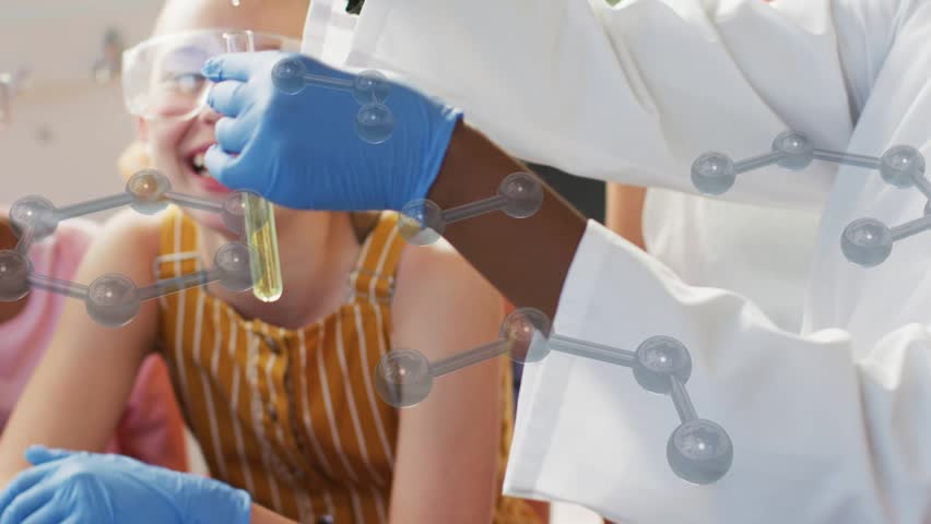 STEM tutor teaching, lifting tube, adding yellow liquid, overlay partly hiding scene, kids smiling. Science, classroom, experiment, goggles, molecule, laboratory, education