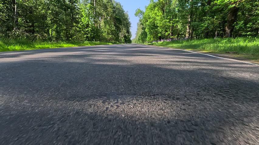 Driving a red car over the road along the asphalt at speed, view from the wheel in motion.