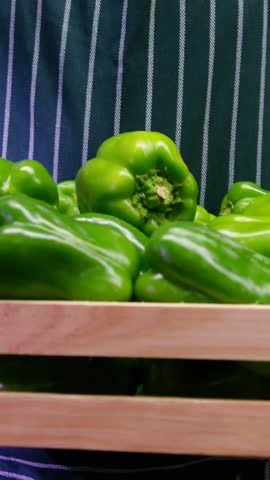 Male staff holding fresh capsicum in wicker basket at organic section of supermarket