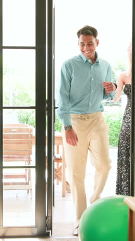 Vertical video: Diverse friends opening door, entering room and spotting birthday cake and balloons. Celebration, friendship, joy, vibrant, modern, social, vertical video