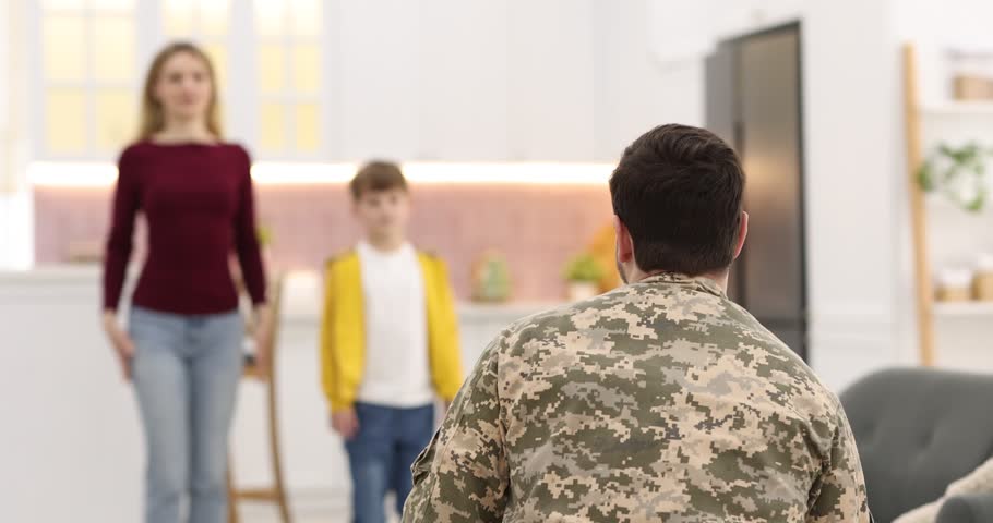 Soldier coming home. Man in military uniform hugging his family