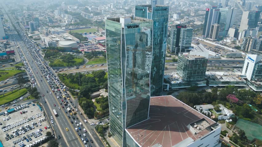 4K aerial close-up of the Westin Hotel skyscraper in Lima, modern glass architecture in the financial district on a sunny day.