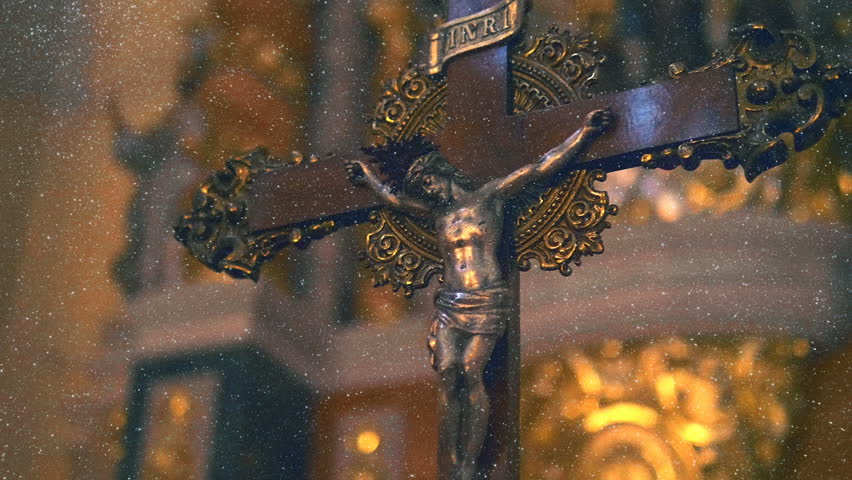 In the Spain inside the ancient church affects the design and richness of decoration and the cross with Jesus Christ. View through sparkling particles. Shot in motion