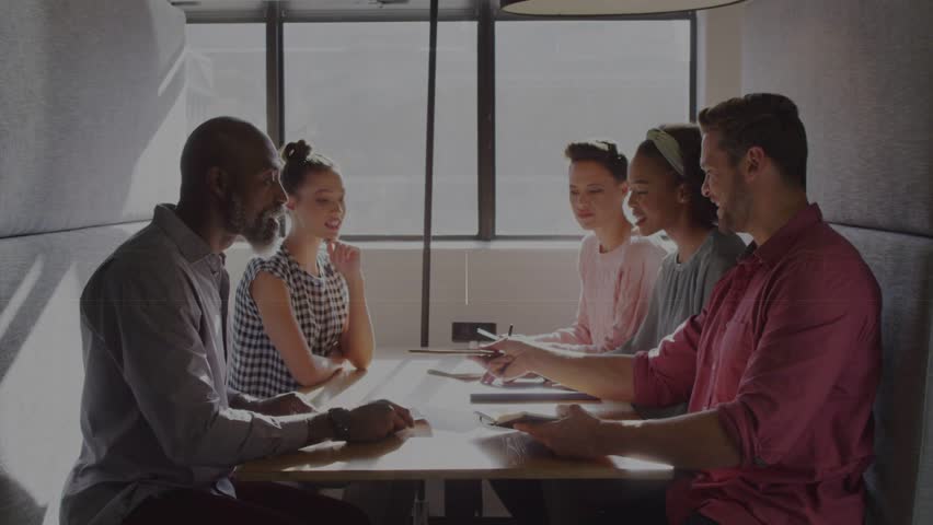 Five people sitting in booth, man in red tapping tablet and HUD overlays animating cybersecurity. Collaboration, teamwork, office, interface, panel, data, backlight