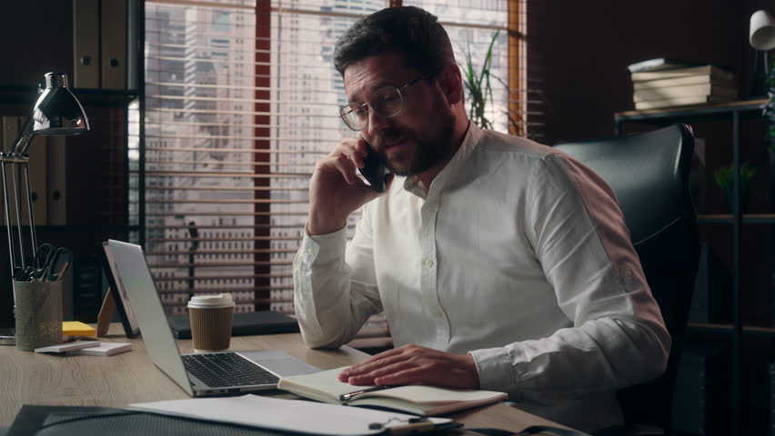 Laughing Caucasian business man talking mobile phone in office happy boss businessman discussing startup project male employer show OK approval gesture entrepreneur working call indoors communication