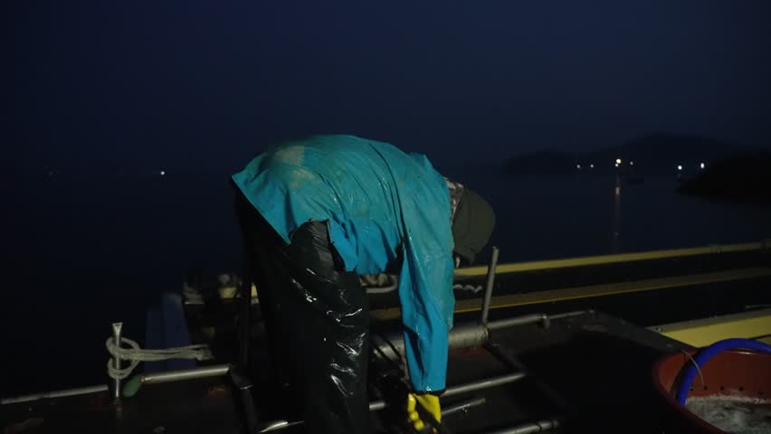Back view of a fisherman mooring a boat with a rope in the early morning