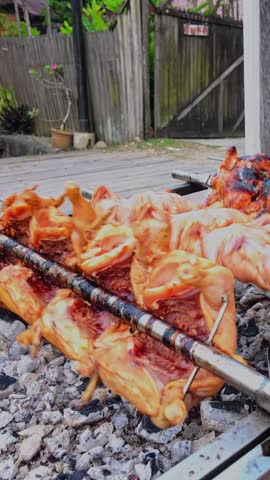 several pieces of chicken are roasted in a roasting machine at street bazaar