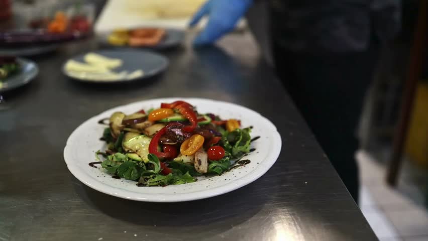 Delicious salad with mixed vegetables and balsamic glaze on a white plate