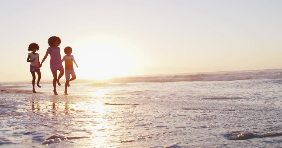 Woman with two children walking, social icons appearing over water, engaging shapes for creators. Beach, sunset, silhouette, reflections, waves, family, backlit