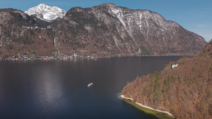 Drone view looking down at a large lake surrounded by mountains and forest.
