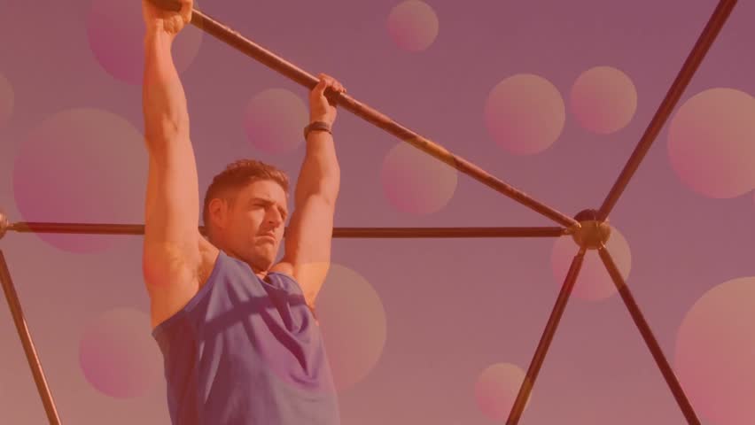 Man gripping geodesic bar and initiating hanging leg raises for fitness, pink bokeh showing reps. Calisthenics, outdoor, athletic, pullup, frame, metal, lowangle