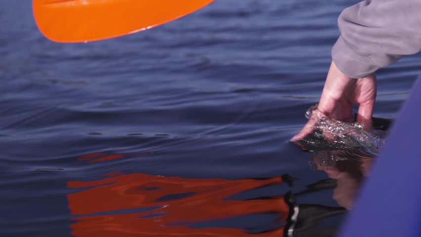 A woman paddles a kayak down a calm river. Active water recreation.