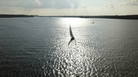 Aerial View Following Sailboat on Reflective River