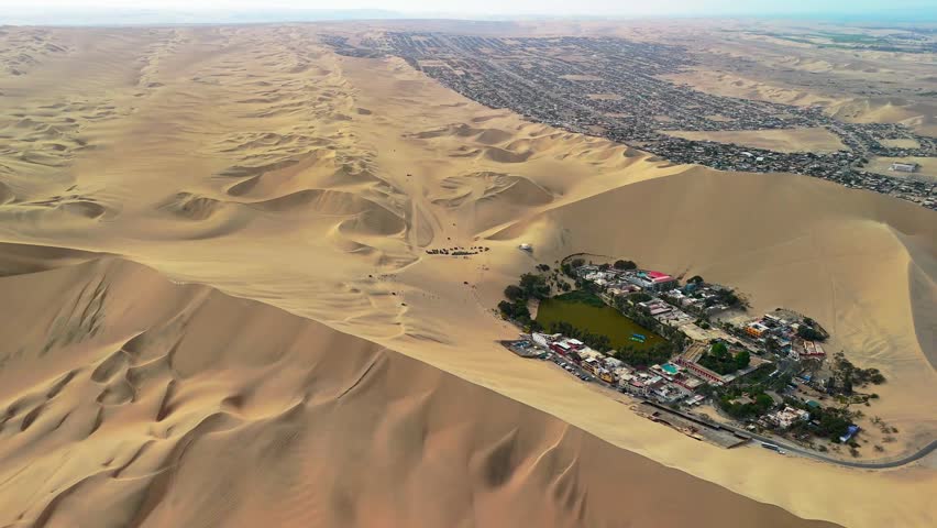Aerial drone view of a desert landscape with the Huacachina oasis, sand dunes and the city of Ica. Peru