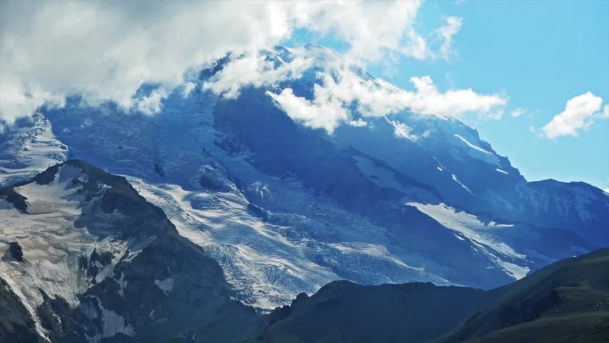 view of the majestic, snow-capped Mount Rainier, seen from the rugged landscape of the Burroughs Mountain Trail in Mount Rainier National Park, Washington.