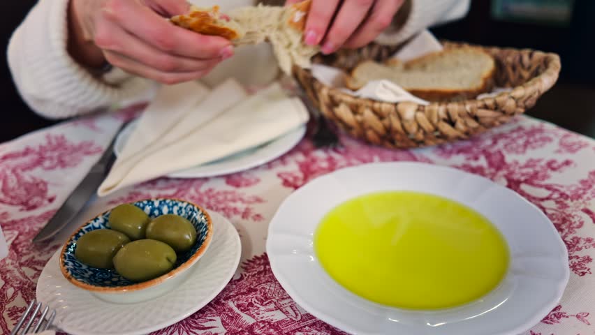 Dipping bread into olive oil a delicious appetizer with olives and crusty bread.