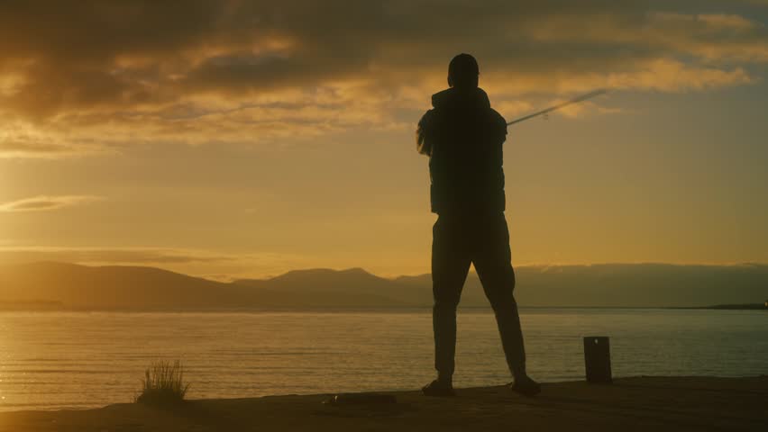 Silhouette of a fisherman casting along a Norwegian shoreline at sunset, with golden light reflecting on calm water and mountains in the distance creating a cinematic scene.