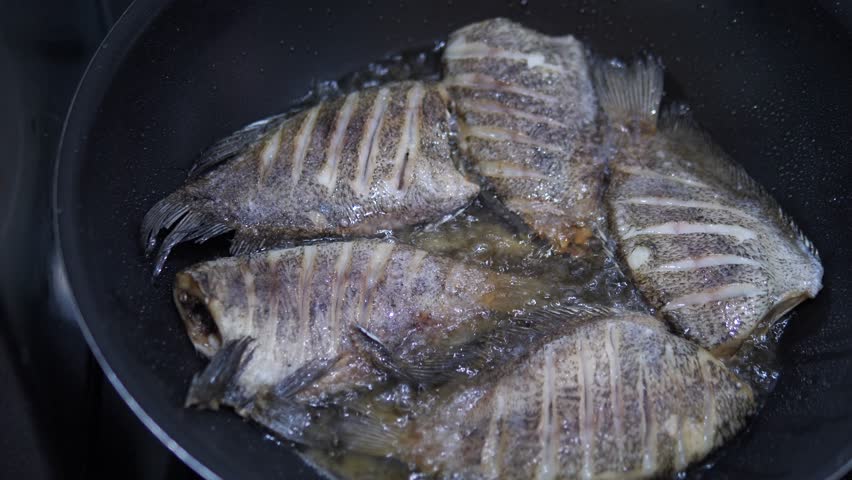 Extreme cinematic close-up of whole fish frying in a pan with sizzling hot oil, golden brown crispy texture, Asian home cooking concept