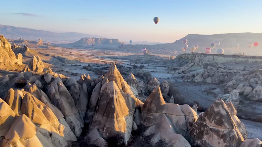 Aerial view of Love Valley Cappadocia taken hot air balloon with tall fairy chimneys and soft morning light under clear blue sky landscape