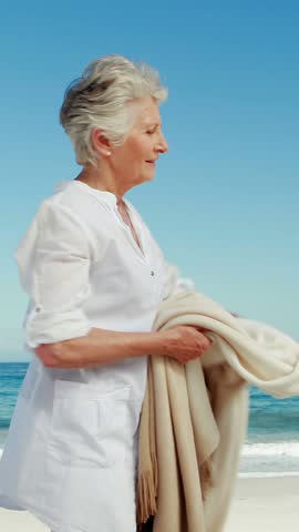 Senior woman wearing coat at the beach