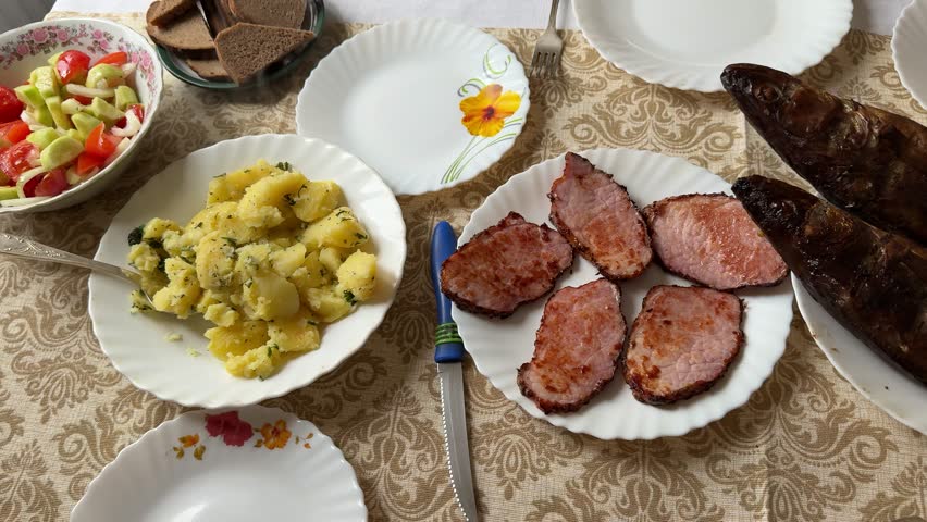 Smoked walleye and pork steaks arranged on white plates with boiled potatoes tossed in herbs, sauerkraut, fresh salad, dark rye