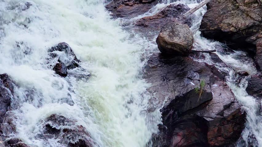 Rushing waterfall through a rocky mountain canyon in a location resembling Rocky Mountain National Park, capturing scenic whitewater, conifer forest, and rugged Colorado outdoor beauty.