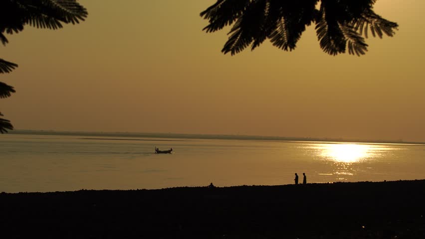 People and fisherman boat on the beach at sunset, beautiful coastal landscape.