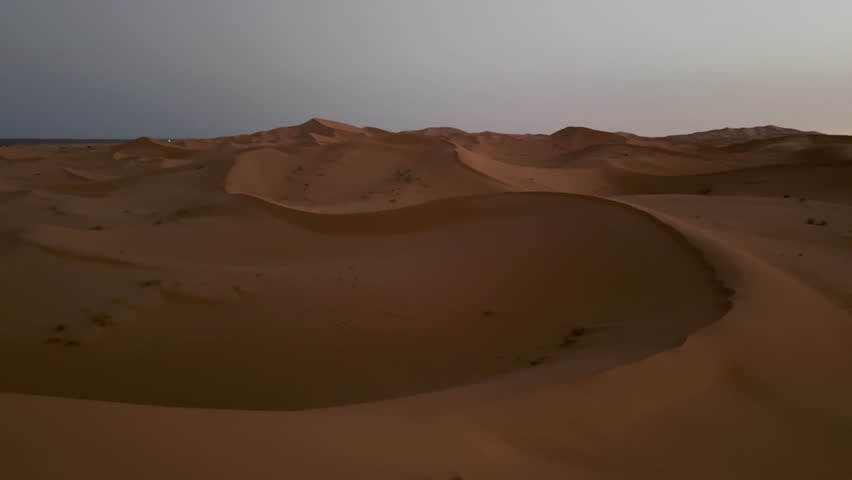 Beautiful pastel-colored clouds moving over the Sahara Desert sand dunes during a tranquil sunset, tc01