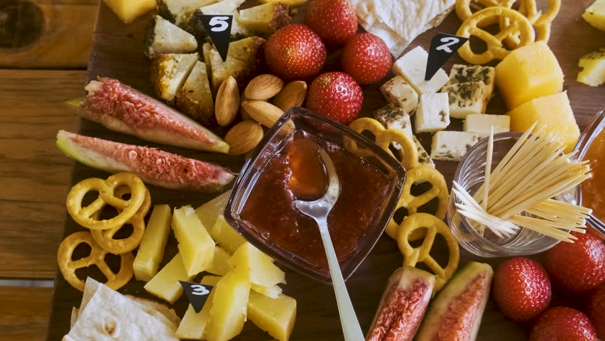 Top view of assorted cheese platter with fresh figs, strawberries, nuts, pretzels and fruit jam on rustic wooden table. Cheese board. Appetizer and party food tasting