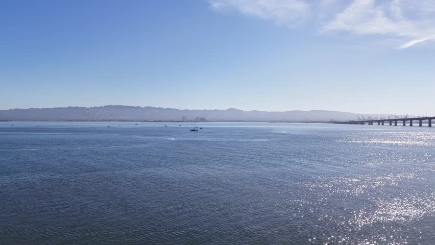 Beautiful aerial view from Treasure Island showing the San Francisco Bay, with the Oakland shoreline and the bay bridge visible on the horizon under a clear blue sky on a sunny morning