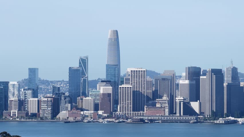 Beautiful morning aerial view of the San Francisco downtown skyline and financial district, with the iconic Salesforce Tower and city skyscrapers reflecting on the calm waters of the bay