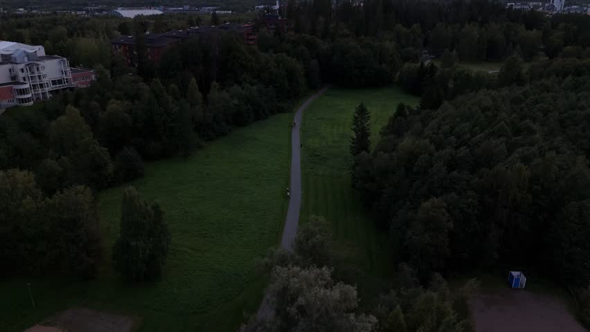 Aerial view of park path in Nuuksio National Park Espoo Finland with trees and walkers, distant water and soft dusk light creating calm outdoor natural environment