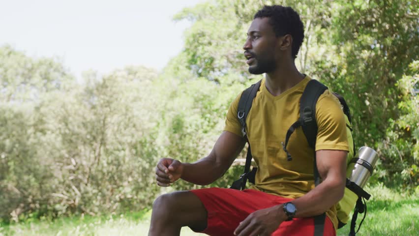 Man sitting scanning, camera zooming, animated grid aligning near backpack showing navigation. Hiking, outdoors, trail, sunlit, watchful, gear, markers