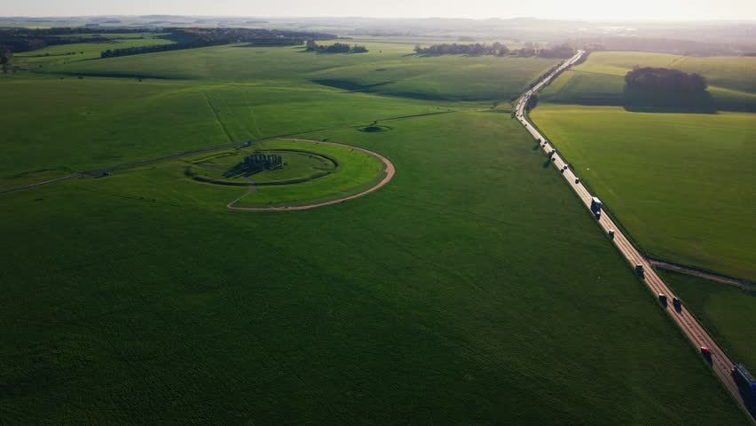 Aerial view of Stonehenge surrounded by green countryside in Wiltshire England showing the historic stone circle and rural landscape at golden hour