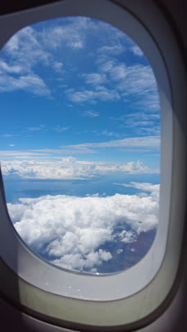 View from airplane window showing wing over clouds. Travel by air and vacation concept. Vertical video 4k
