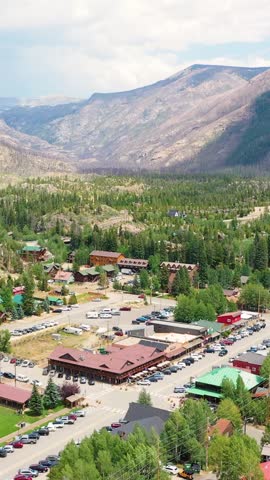 Portrait video aerial view of Grand Lake Colorado with shoreline homes, calm blue water, wooded peninsulas, and mountain ridges surrounding a scenic alpine lake in bright summer daylight