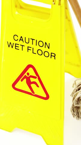 Mop with wet floor caution sign against white background