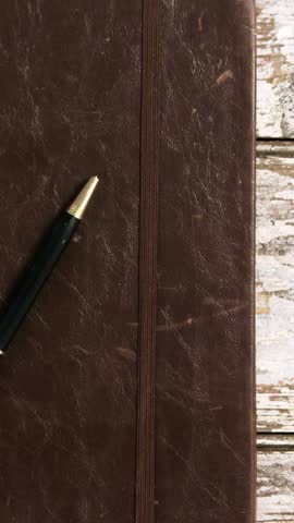 Diary with pen, cup of tea and smartphone on wooden surface