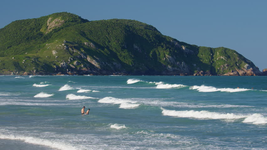 Santinho beach with people relaxing near the water. Florianopolis, Brazil