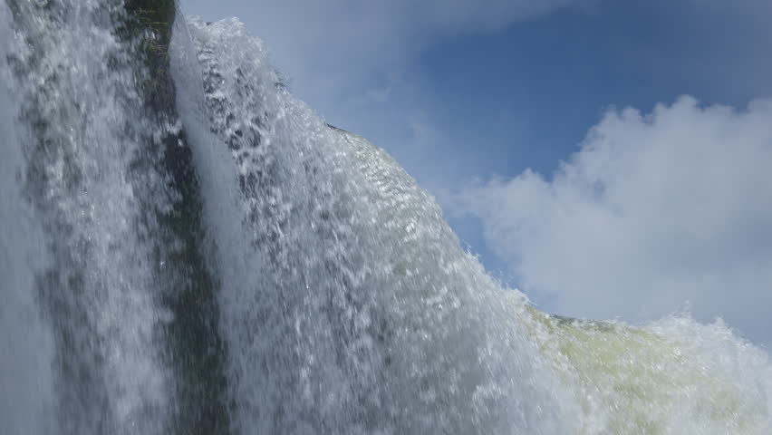 Powerful Iguazu waterfall with massive water flow, mist and foam under cloudy sky